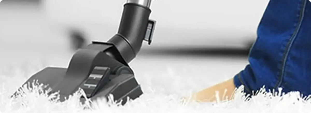 Close-up of a professional vacuuming a white carpet in Apex.